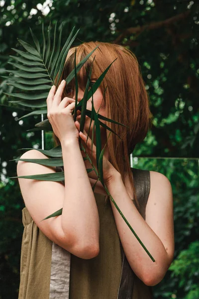 En tjej ser genom en gren av en ormbunke — Stockfoto