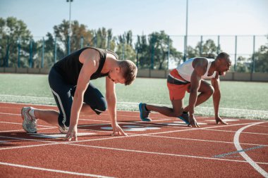 Siyah bir koşucu onun dilini çıkarmış başında beyaz adamın yanında duruyor
