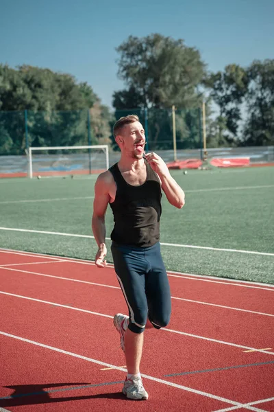 Um atleta de bigode alegre lambe um pirulito — Fotografia de Stock