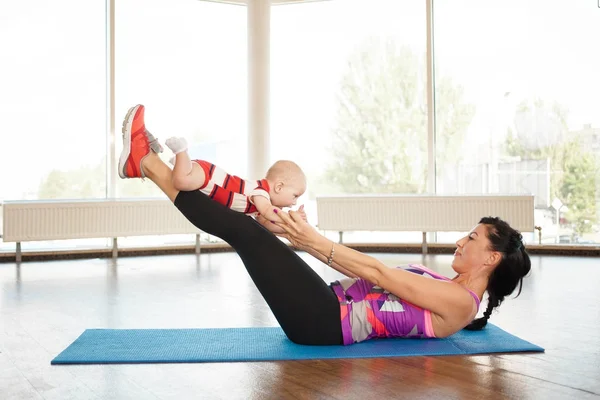 A young mother shakes her legs with the help of a small child