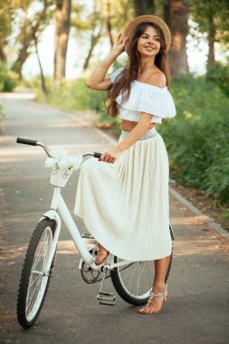 Güzel kız gülümser ve bir bisiklet üzerinde oturur