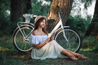 Çimenlerin üzerinde seyir telefon ve gülümseyerek oturan kız