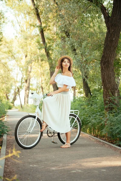 Uma menina está sentada em uma bicicleta em um vestido — Fotografia de Stock