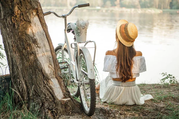 Genç bir kızın yanında yaşlı bir ağaç sahilde