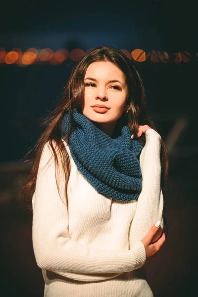 Девушка в белом свитере и шарфе ночью — стоковое фото