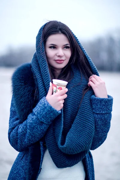 Ritratto di una giovane donna in cappotto con un colletto che beve caffè per strada — Foto Stock