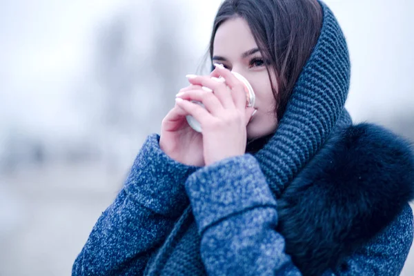 Porträt einer jungen Frau im Mantel mit Kragen, die auf der Straße Kaffee trinkt — Stockfoto