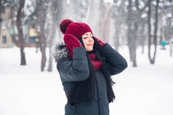 A young woman in mittens straightens her hat