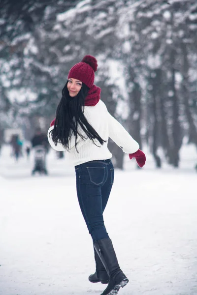 A girl in jeans and a white sweater runs through the snow