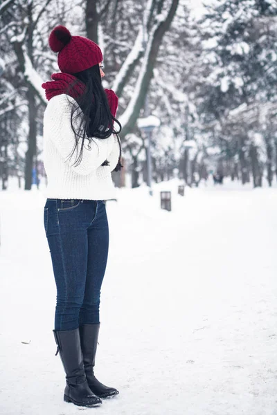 Een meisje in jeans en een witte trui loopt door de sneeuw Rechtenvrije Stockfoto's