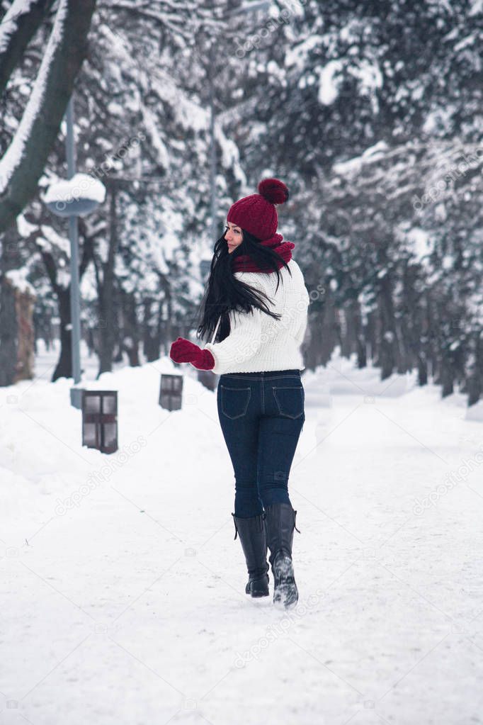A girl in jeans and a white sweater runs through the snow