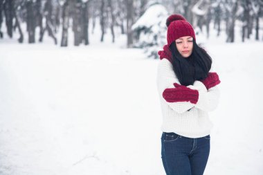 Tatlı, ihale ve şehvetli genç bir kadın beyaz bir kazak ve parlak bir şapka, eşarp ve eldiven