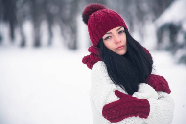 Tatlı, ihale ve şehvetli genç bir kadın beyaz bir kazak ve parlak bir şapka, eşarp ve eldiven