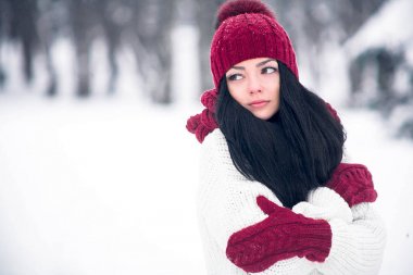 Tatlı, ihale ve şehvetli genç bir kadın beyaz bir kazak ve parlak bir şapka, eşarp ve eldiven