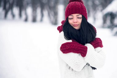Tatlı, ihale ve şehvetli genç bir kadın beyaz bir kazak ve parlak bir şapka, eşarp ve eldiven