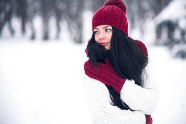 Tatlı, ihale ve şehvetli genç bir kadın beyaz bir kazak ve parlak bir şapka, eşarp ve eldiven