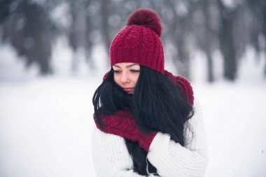 Tatlı, ihale ve şehvetli genç bir kadın beyaz bir kazak ve parlak bir şapka, eşarp ve eldiven