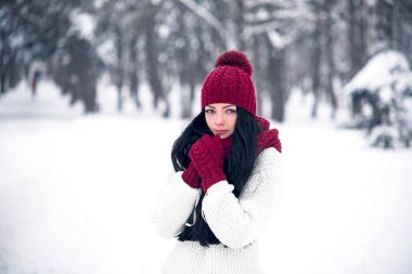 Tatlı, ihale ve şehvetli genç bir kadın beyaz bir kazak ve parlak bir şapka, eşarp ve eldiven