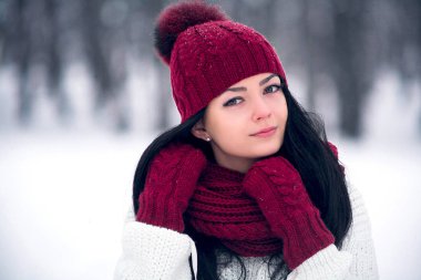Tatlı, ihale ve şehvetli genç bir kadın beyaz bir kazak ve parlak bir şapka, eşarp ve eldiven