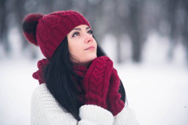 Tatlı, ihale ve şehvetli genç bir kadın beyaz bir kazak ve parlak bir şapka, eşarp ve eldiven