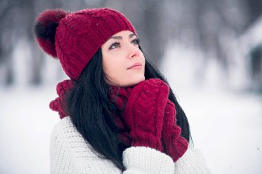 Tatlı, ihale ve şehvetli genç bir kadın beyaz bir kazak ve parlak bir şapka, eşarp ve eldiven