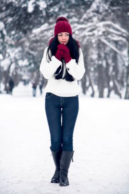 Tatlı, ihale ve şehvetli genç bir kadın beyaz bir kazak ve parlak bir şapka, eşarp ve eldiven