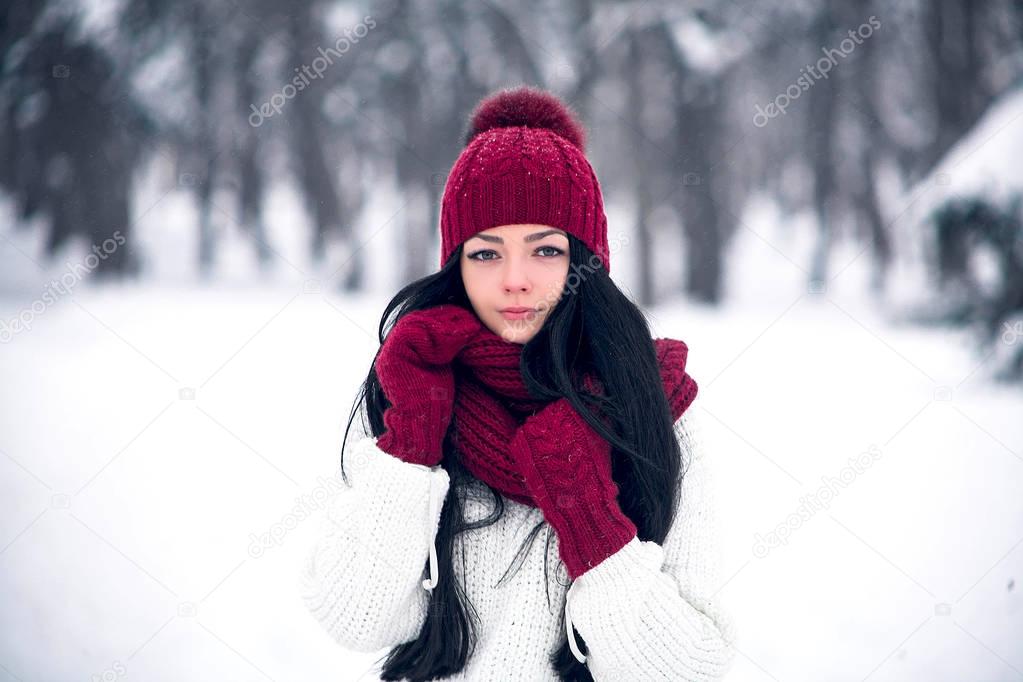 A sweet, tender and sensual young woman in a white sweater and a bright hat, scarf and mittens