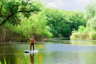 Uzaktan Nehri üzerinde bir adam bir sup tahta üzerinde yüzüyor