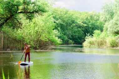 Uzaktan Nehri üzerinde bir adam bir sup tahta üzerinde yüzüyor