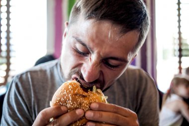 Genç biri hamburger yemek