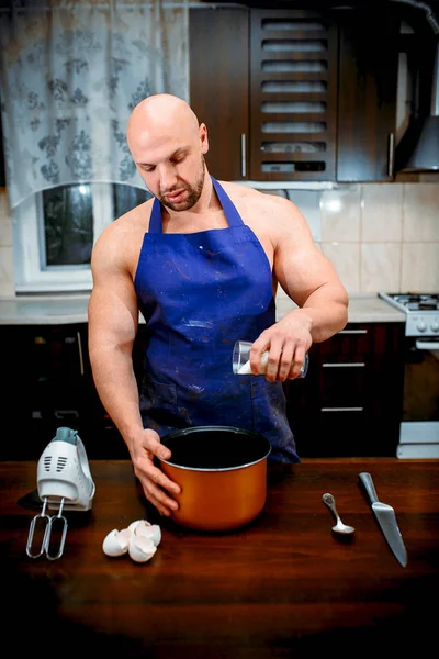 A young man is cooking in a large kitchen