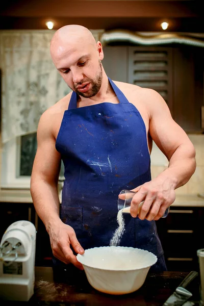 A young man is cooking in a large kitchen