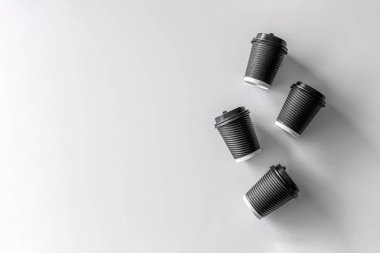 Beyaz masa arkasında siyah kağıt bardak kahve.