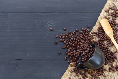 Kahve çekirdeği ve kahve fincanı siyah ahşap arka planda. en üstteki görünüm