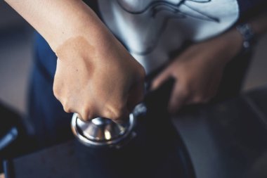 Barista 'nın yakın çekimi yumuşak odaklı kahve yapıyor ve arka planda ışık var.