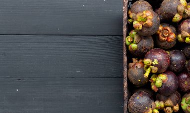 Siyah ahşap masanın üzerinde yakın plan mangosteen meyvesi. en üstteki görünüm