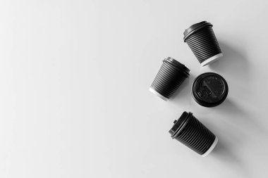 Beyaz masa arkasında siyah kağıt bardak kahve.