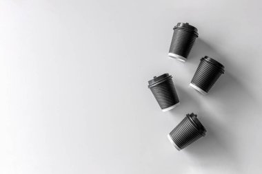 Beyaz masa arkasında siyah kağıt bardak kahve.