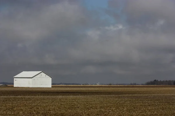 Granero blanco en un campo en un día nublado — Foto de Stock