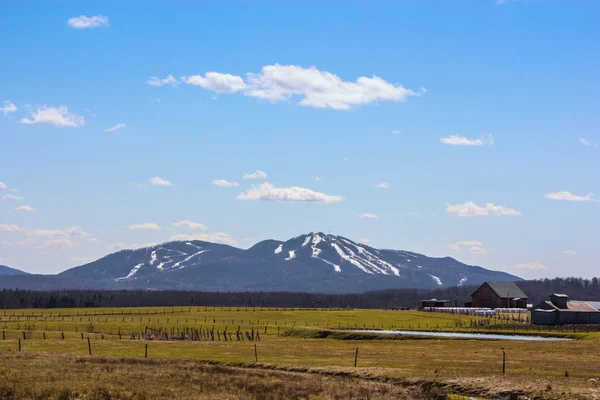 ski mountain in spring with agricultural field in front