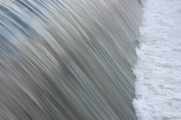 Nahaufnahme fließenden Wassers über Flussdamm — Stockfoto