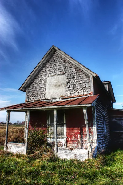 Vieja casita abandonada con cielo azul y hierba verde — Foto de Stock