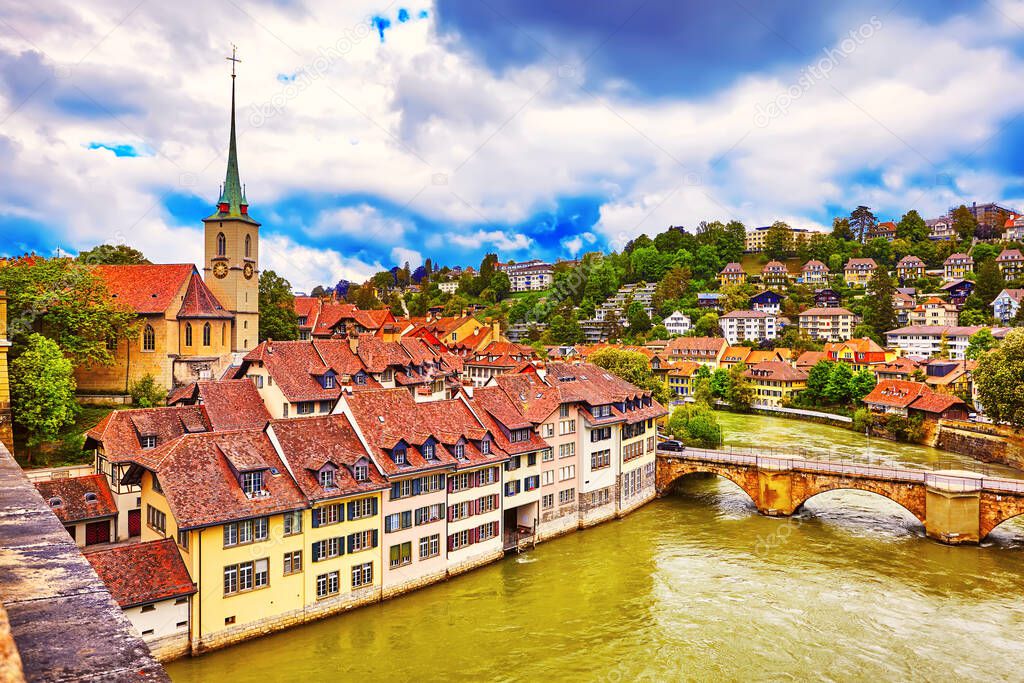 The Historical Old Town of Bern city, tiled roofs, bridges over Aare river and church tower on dramatic sunset, Switzerland