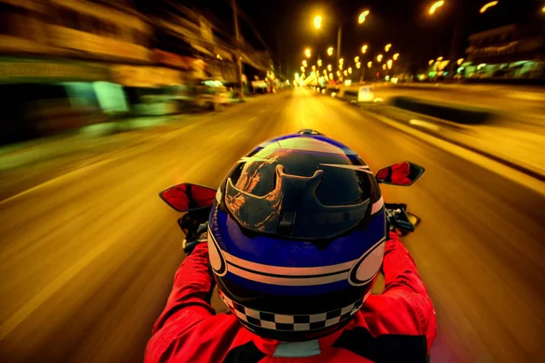 Mann fährt Motorrad auf Nachtstraße mit hoher Geschwindigkeit wegen Bewegungsunschärfe Stockbild