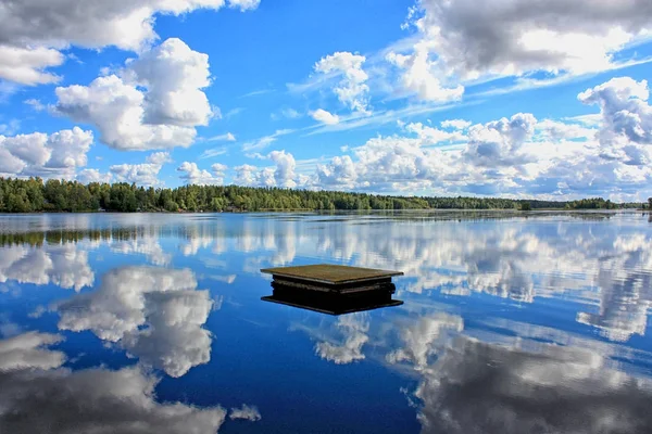 Molnig himmel och docka reflektion på vattnet — Stockfoto
