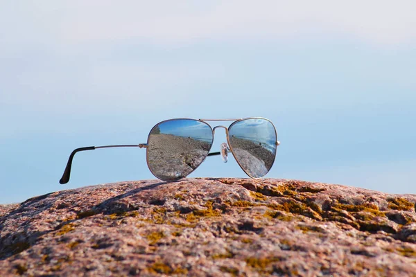 Sluneční Brýle Odleskem Pláž Leží Kameni Izolované Pozadí Modré Oblohy — Stock fotografie