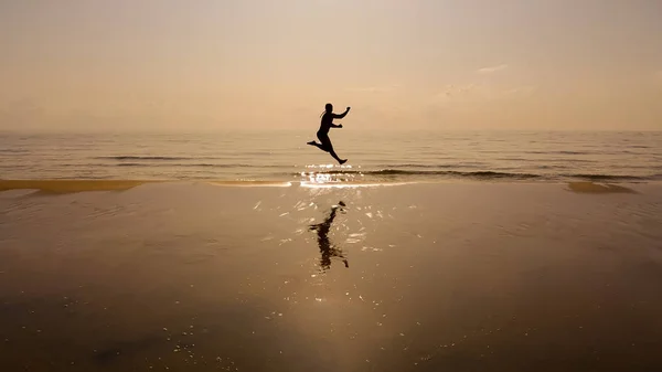 Sylwetka Szczęśliwy Człowiek Podróżnik Skakać Wodzie Morza Plaży Okresie Letnim — Zdjęcie stockowe