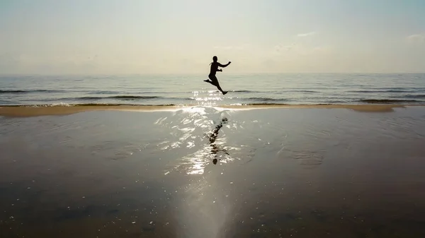 Sylwetka Szczęśliwy Człowiek Podróżnik Skakać Wodzie Morza Plaży Okresie Letnim — Zdjęcie stockowe