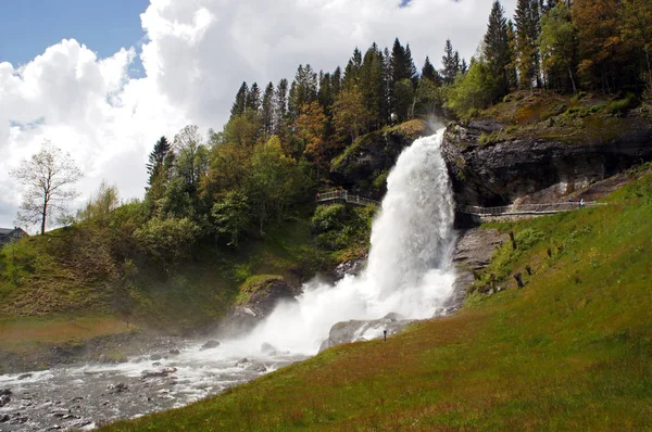 Steinsdalsfossen cascata nel fiume Steine paesaggio panoramico con cascata circondata da montagne e tradizionali norvegia, case scandinave — Foto Stock