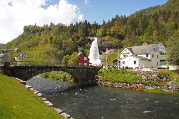 stock image Steinsdalsfossen waterfall in the river of Steine - scenic landscape with cascade surounded by mountains and traditional norvegian, scandinavian houses